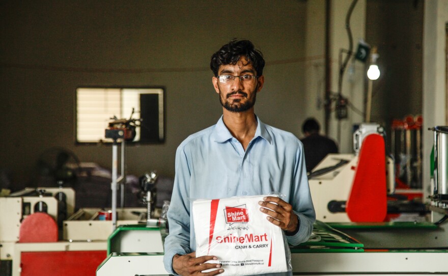 Mohammad Zaheer holds up bags freshly stamped with supermarket slogans. He says he's worried about his future after the plastic bag ban begins. He says that if he has to find another job, "it will be difficult, because there is much unemployment."