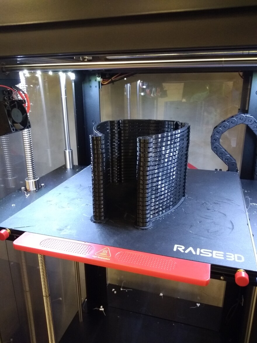 A platform inside of a 3D printer. A portion of the protective visors were completed with a 3D printer in ABS plastic.