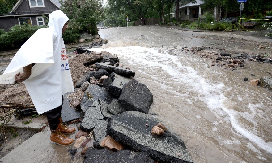 John Hoffenberg watches as floodwaters flow down a street in Boulder, Colo., on Sunday.