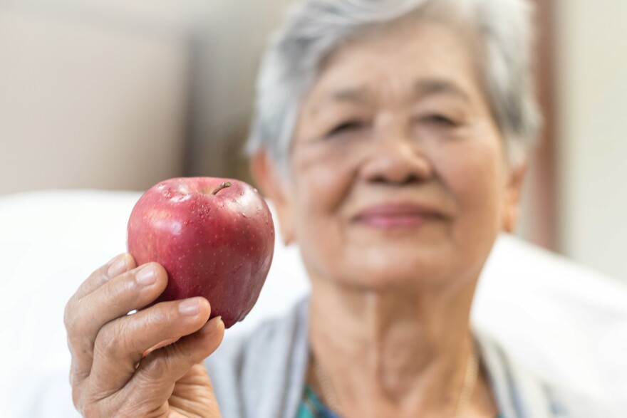 Cholesterol diet, diabetes control and healthy food nutritional eating for cardiovascular disease risk reduction for old people concept.Senior woman holding apples, super fruit.