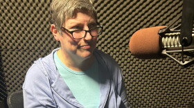 Tracy Adkins, author of Ghosts of Athens: Ghosts of Athens: History and Haunting of Athens, Georgia. A middle-aged, fair-skinned woman with a blonde pixie cut wearing a light-blue zip-up sweatshirt, sitting in a studio with padded walls.