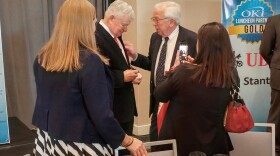 Bob Castellini, (center left), signs a baseball after speaking at the OKI luncheon Tuesday.