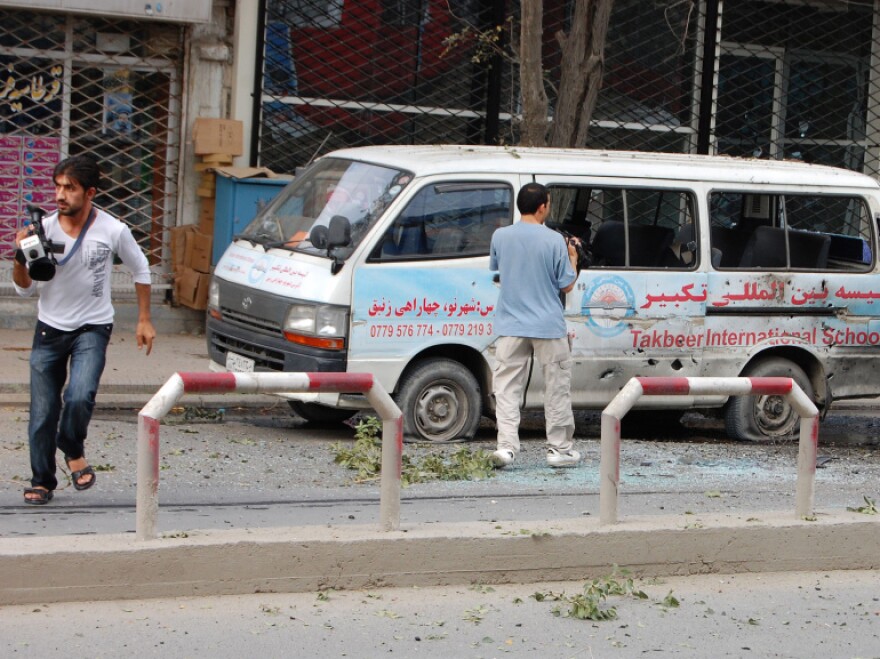 Journalists stand near a bullet-ridden van during Tuesday's attack in Kabul.