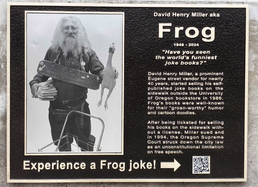 Sign reads Frog,1948-2024. "Have you seen the world's funniest joke books?" David Henry Miller, a prominent Eugene street vendor for nearly 40 years, started selling his self-published joke books on the sidewalk outside the University of Oregon bookstore in 1986. Frog's books were well-known for their "groan-worthy" humor and  cartoon doodles. After being ticketed for selling his books on the sidewalk with-out a license, Miller sued and in 1994, the Oregon Supreme Court struck down the city law as an unconstitutional limitation on free speech.