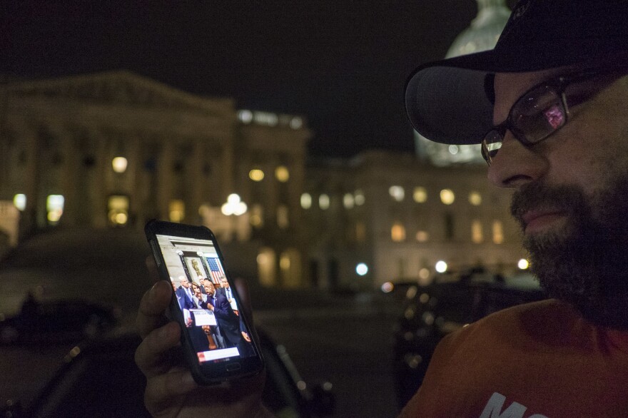 Outside the U.S. Capitol on Thursday, a supporter watches the proceedings being live-streamed from the House floor by Democrats taking part in a sit-in.
