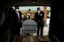 In this Saturday, April 18, 2020 photo, mortician Cordarial O. Holloway, foreground left, funeral director Robert L. Albritten, foreground right, place a casket into a hearse in Dawson, Ga.