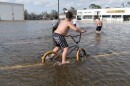 Children ride bikes and march through floodwaters in the parking lot of a Dollar General in Terrebonne Parish, La. on Aug. 30, 2021, after Hurricane Ida blew through the region.