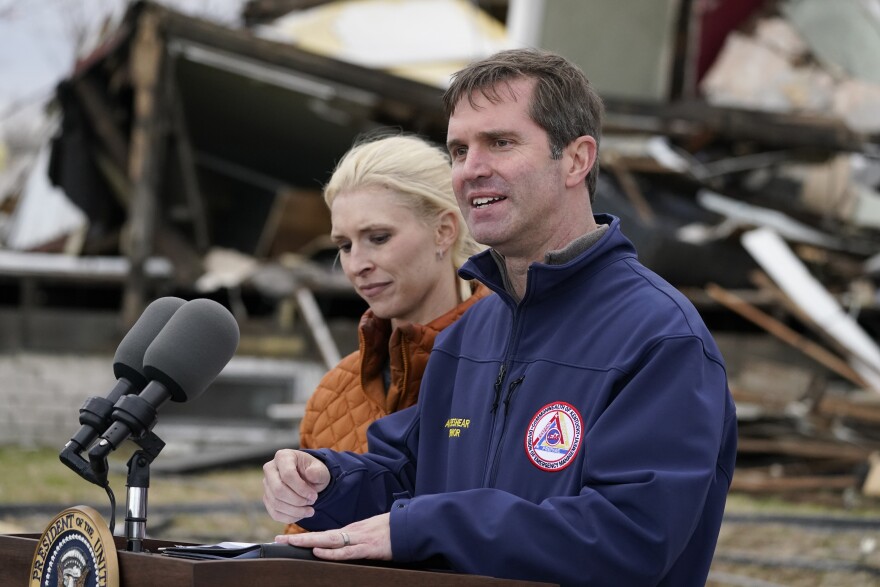 Kentucky Gov. Andy Beshear, standing next to his wife Britainy Beshear, speaks after surveying storm damage from tornadoes and extreme weather in Dawson Springs, Ky., Wednesday, Dec. 15, 2021.