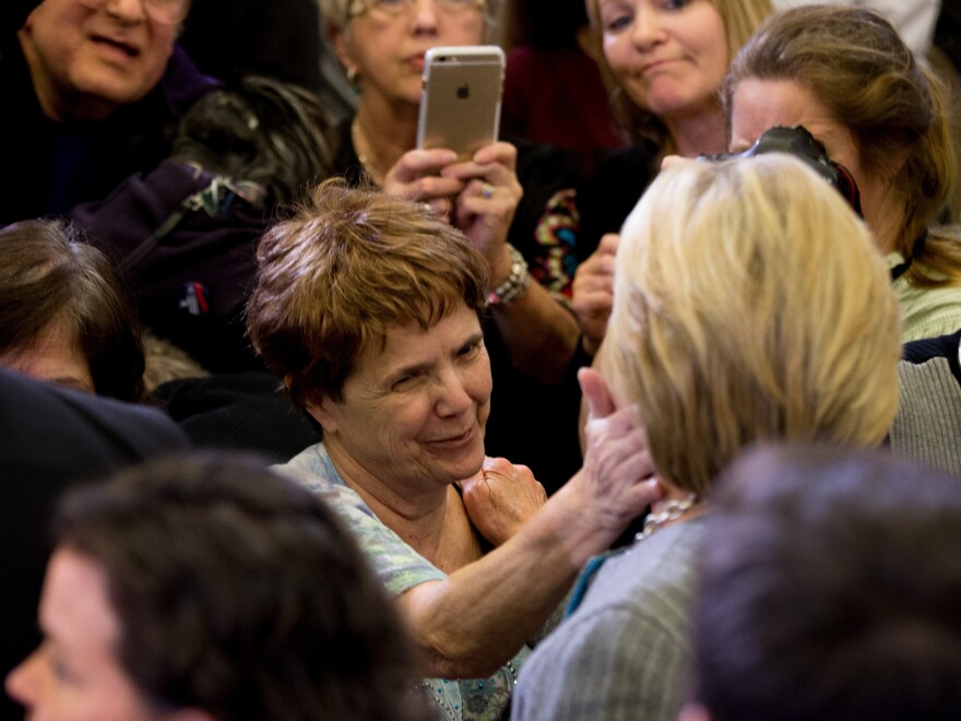 A woman touches the cheek of Democratic presidential candidate Hillary Clinton at a rally in Des Moines, Iowa.