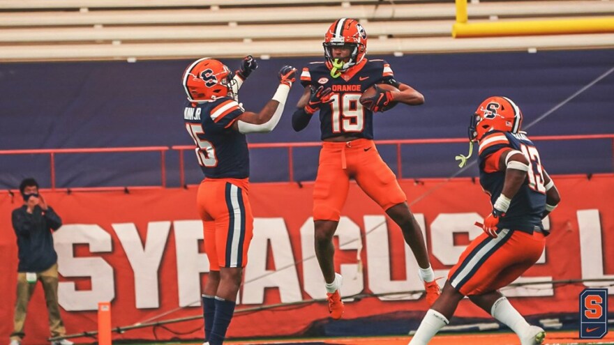 SU's Rob Hanna (middle) celebrates his first career interception with teammates Neil Nunn (left) and Mikel Jones (right).