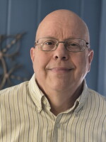 A man with glasses and a button-down dress shirt.
