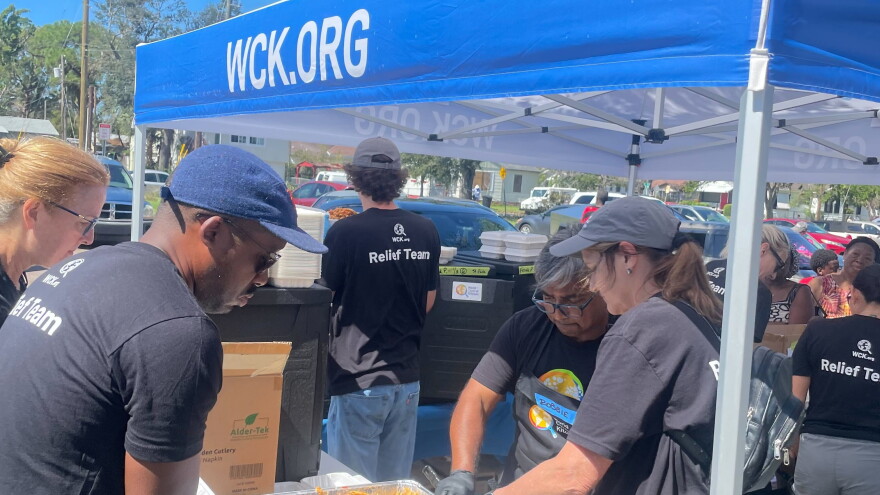 people standing under a tent are preparing meals to provide to people standing in a line