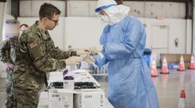 U.S. Army Spc. Gabriel Eiter with the Illinois Army National Guard and Lt. Col. Jim Avery, a flight surgeon with the Air National Guard, handle COVID-19 testing equipment at a drive-thru testing site in Bloomington on Saturday.