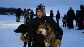 a musher poses with two sled dogs