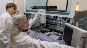A man looks on while a woman touches a big machine.