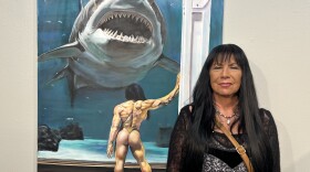 Artist Gloria Mandala poses for a portrait next to her painting, "The Conversation"