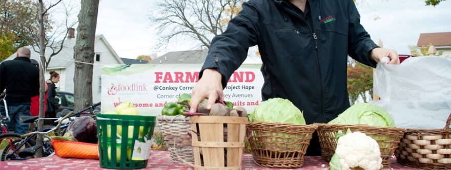 A man places beets into a wooden bucket at a farm stand