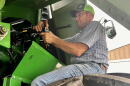 Farmer sits on a tire working on a combine.