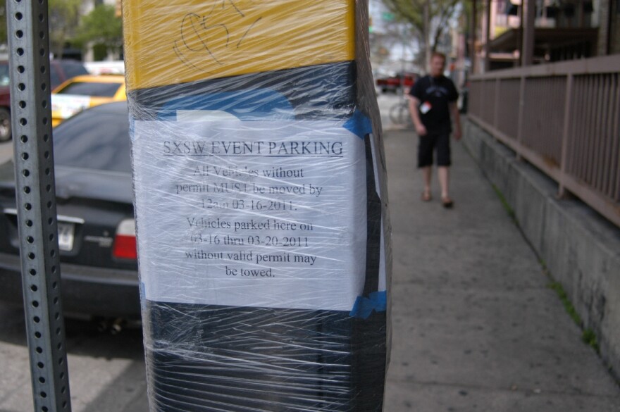 Signs indicate when people need to move their cars off streets that will close. Posts and parking machines are wrapped in plastic to make removal of posters easier after SXSW ends.