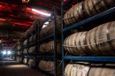 Many barrels filled with bourbon and whiskey line the interior of a barge.