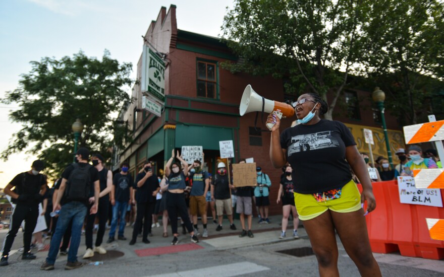 Protest organizer Oluwatoyin Akinmoladun leads the crowd in a chant Saturday evening in front of Kelly’s Westport Inn. The protesters swelled to about 200 and eventually moved to the intersection of Westport Road and Pennsylvania Avenue to continue their protest late into the evening without police intervention.&#13;
