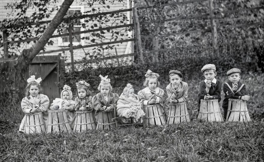 Children pose on baskets in a collection of photos from the turn of the 20th century.