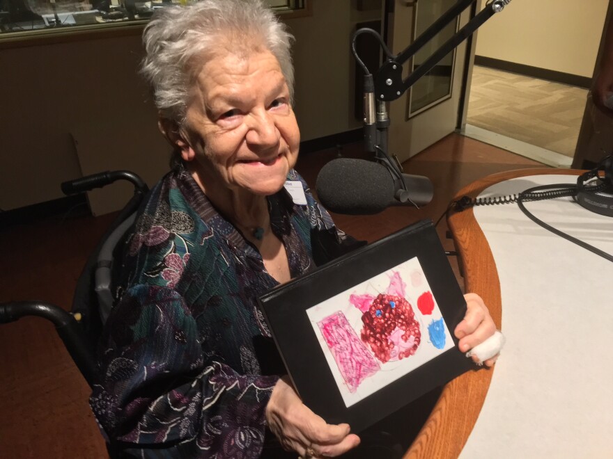 Joanne Savas in the studio holding a piece of a child's artwork