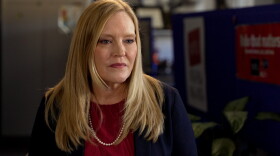 A blonde woman sits in a room.