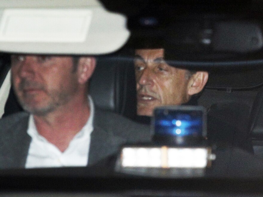 Former French President Nicolas Sarkozy, right, leaves the police station where he was held, in Nanterre, outside Paris, on Wednesday.