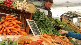A man stands behind fresh produce.