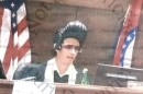 An image of a judge sitting behind the bench who is wearing a dark sunglasses and tall black wig shaped like a pompadour. The image was part of a legal complaint against Judge Matthew Thornhill. 