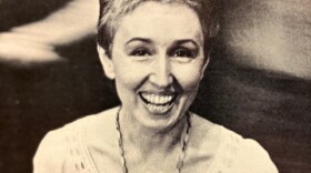 A black and white image of a woman smiling and holding a rose. 