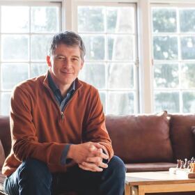 Man sitting on couch looking into camera.