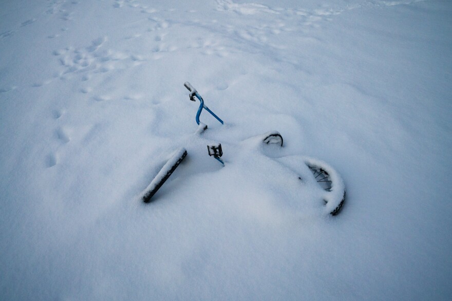 A children's bicycle lays in snow from a recent winter storm.