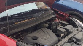 Red kia soul with hood popped. 