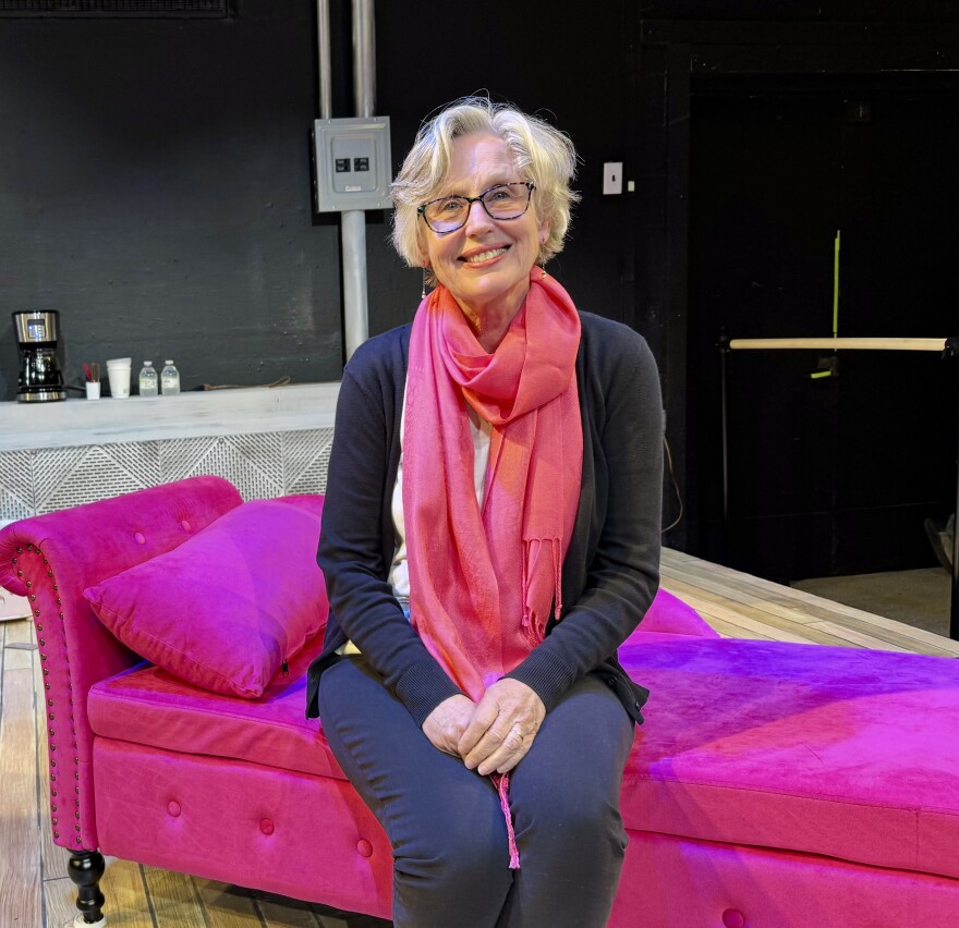 Woman in a pink scarf sits on a couch