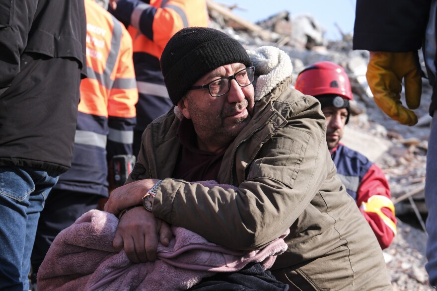 A man watches rescue teams work on a collapsed building to evacuate a victim in Elbistan, Turkey.