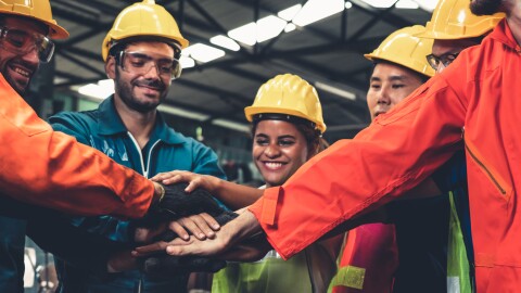 Skillful workers stand together showing teamwork in the factory.