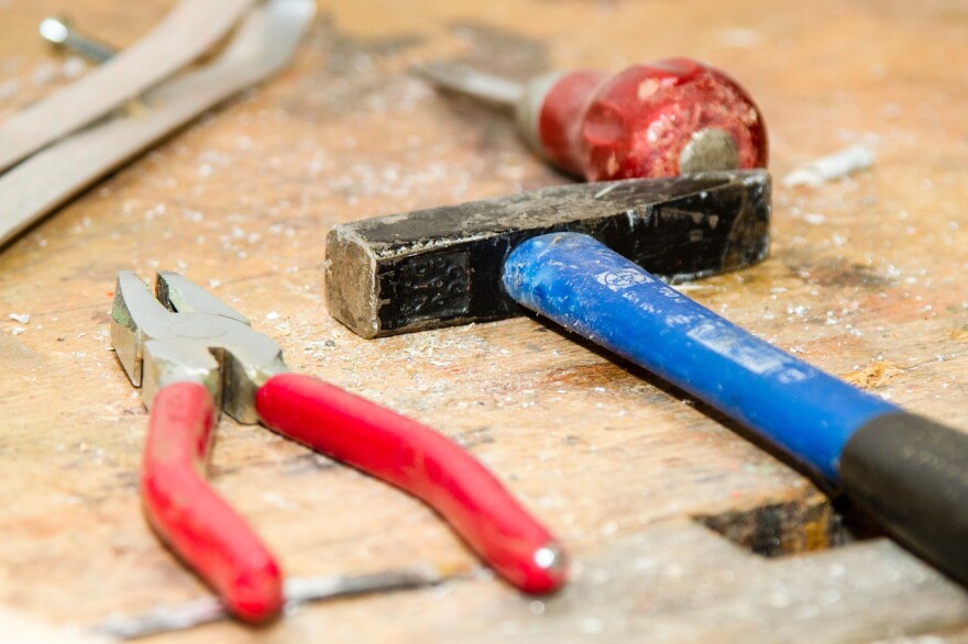 a wrench, hammer and screw driver lay on a table