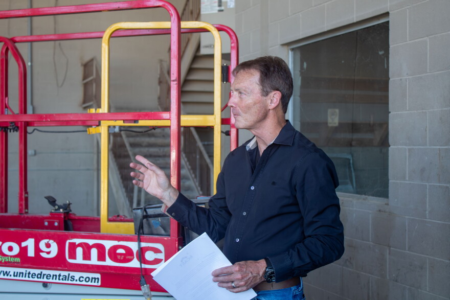 Kyle motions to a covered area outside the building where the 16 mobile laboratory units will be assembled.
