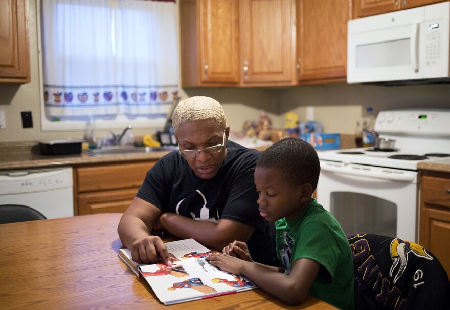 Erica Jones reads with her grandson, Jakeem, at their Florissant home. Jones has lost a daughter and a godson due to guns in recent years.