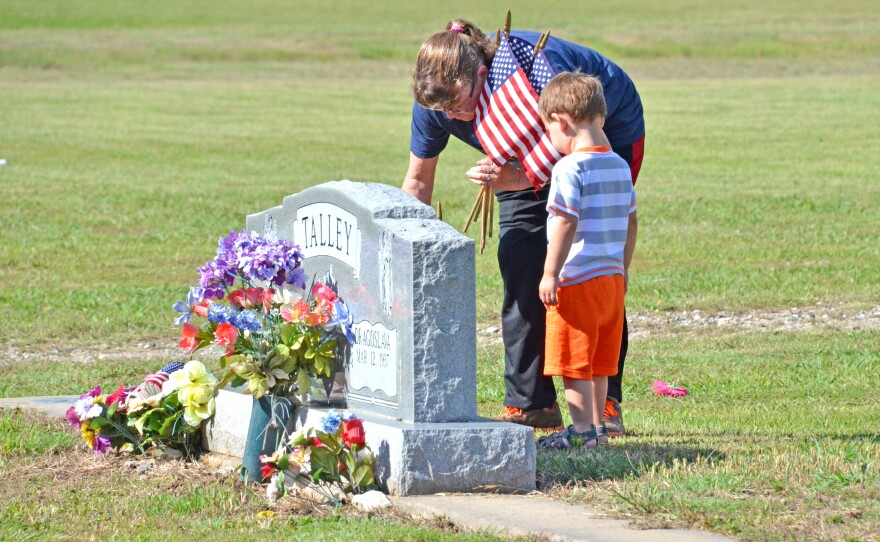 Tammi Springett and her grandson Landon Fouse place a flag on the headstone of LC Talley at Oaklawn Cemetery in Cooper for the Memorial Day holiday.