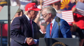 two men shake hands behind podium