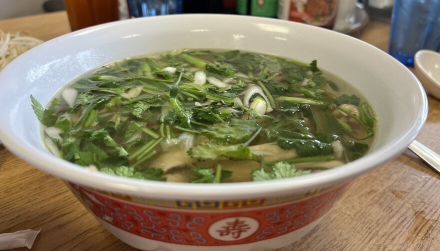 A close-up of a bowl of pho, with various ingredients floating on top of the broth.