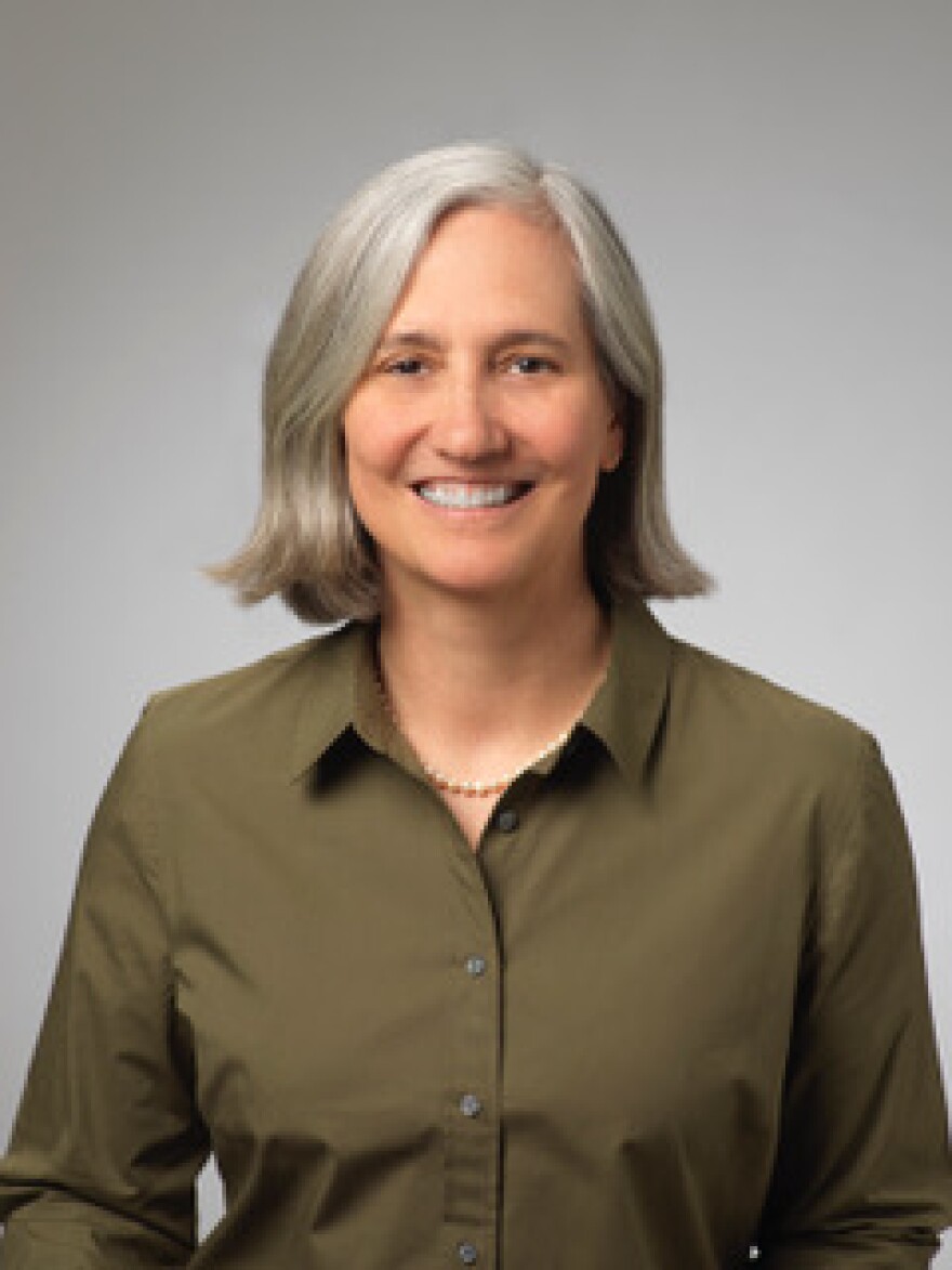 Headshot of Jenny Brekhus. Woman wearing olive green blouse and smiling.