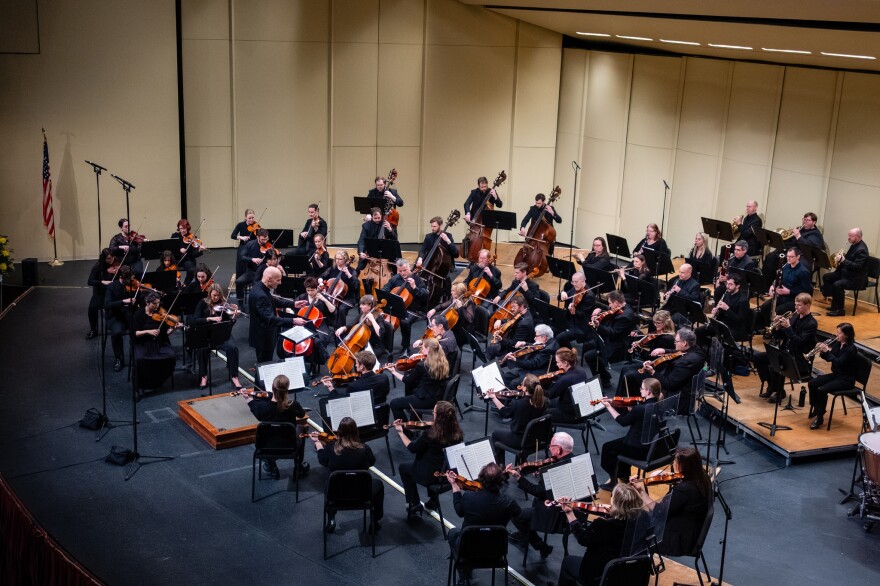 Mark Russell Smith conducting the QCSO in its March 2026 Masterworks program at the Adler Theatre, Davenport, which featured the world premiere of Rebecca Burkhardt's Ballet for Cello and Orchestra, written specifically for QCSO principal cellist Hannah Holman.