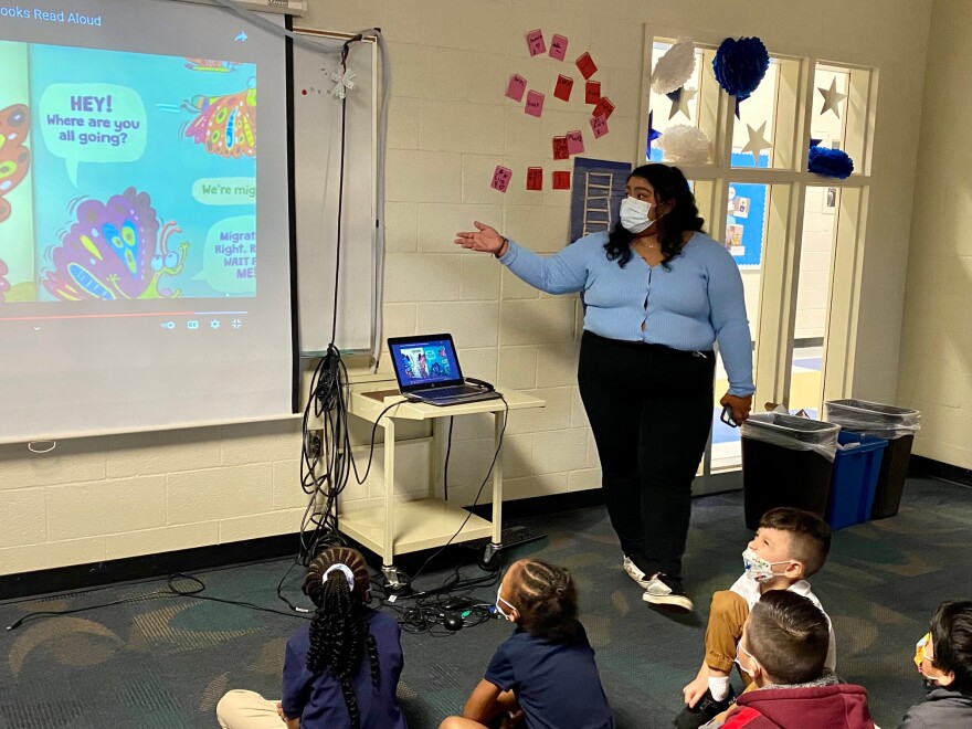 Landy Solorzano, a teacher assistant and high school student at Charlotte Early Teacher College, leads Hickory Grove kindergarteners though a video in the media center.