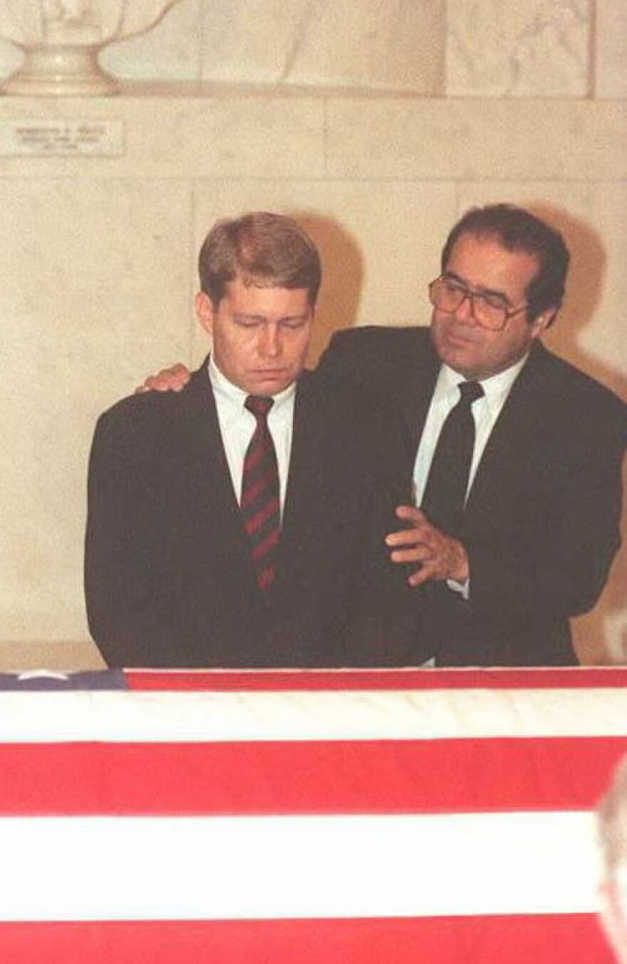 Late Supreme Court Justice Antonin Scalia puts his hand on the shoulder of pallbearer Judge Michael Luttig as they pay their respects at the casket of former Justice Warren Burger in 1995 .