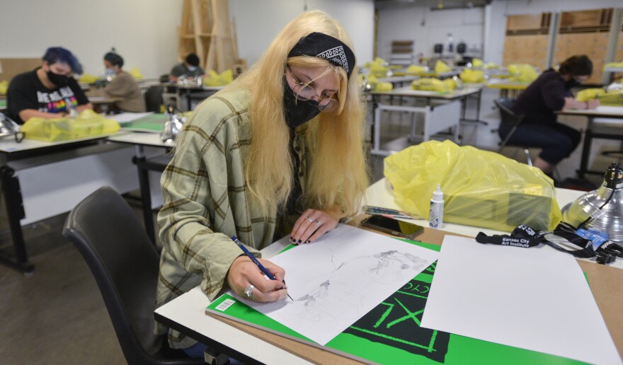 Freshman Claire Litsey, 18, draws a map of the neighborhood where she grew up as part of her first day of classes in foundation studio 101 at the Kansas City Art Institute on Monday. The instructor was teaching from home via a large screen TV in the classroom.