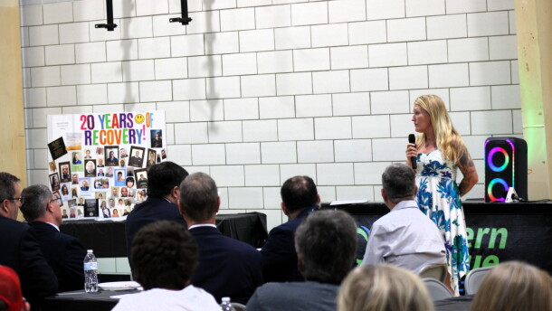 A woman stands in front of a crowd giving a speech